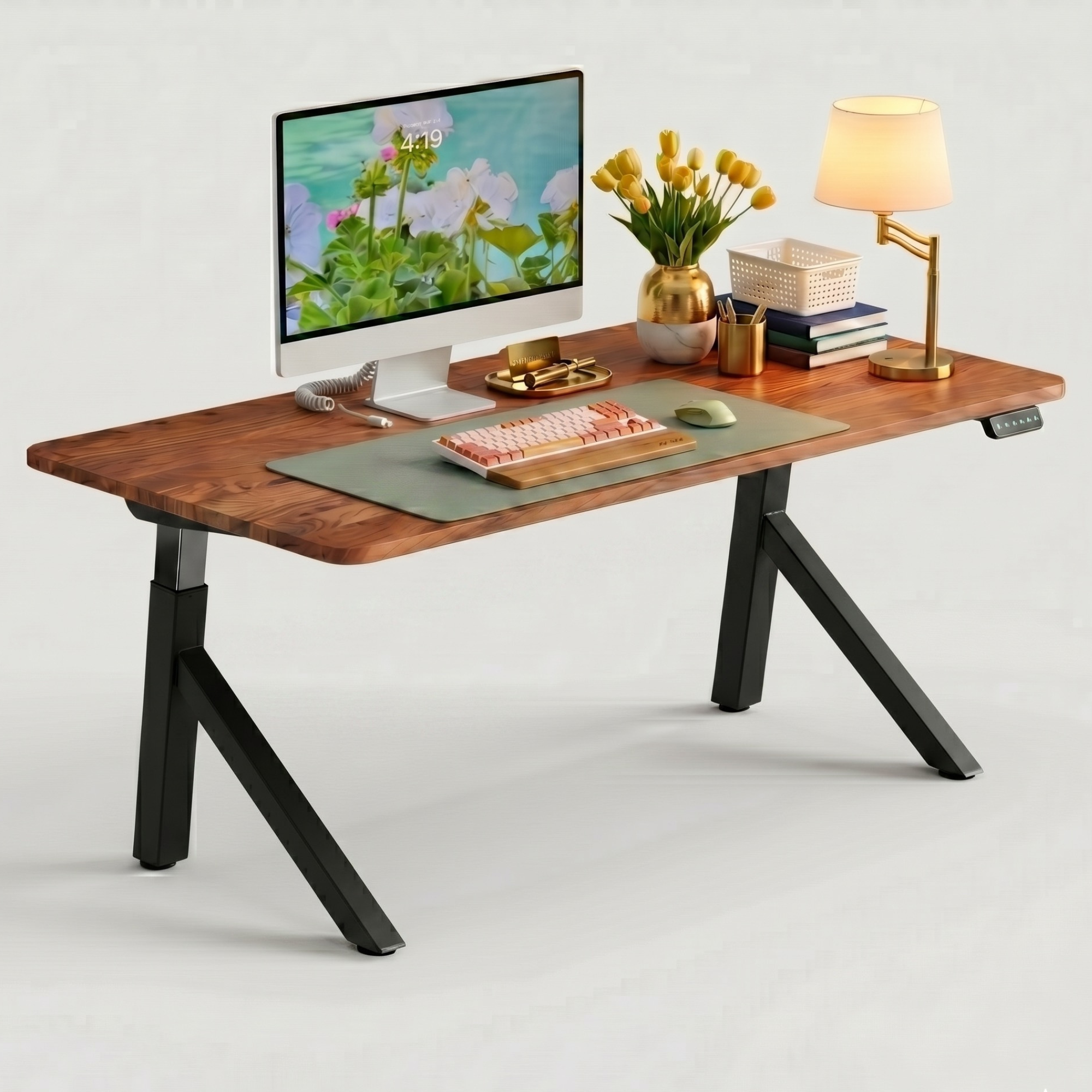 FlowDesk Aero black Y-shape standing desk — angled lifestyle shot with iMac, flowers, warm lamp, keyboard and sage desk mat